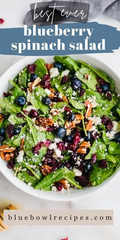 a white bowl filled with blueberry spinach salad on top of a marble counter