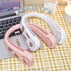 two pink and white hair dryers sitting on top of a laptop computer next to each other