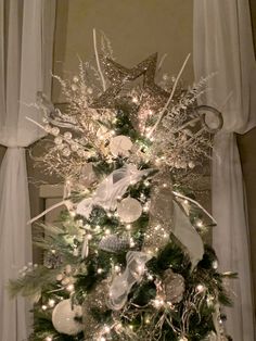 a decorated christmas tree with silver and white ornaments