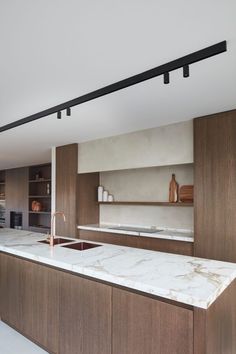 a modern kitchen with marble counter tops and wooden cabinetry, along with stainless steel faucets