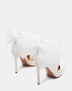 a pair of white high heels with bows on the toes and heeled shoes that are covered in lace