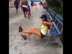 a woman is sitting on a bench in the middle of a crowded area with people walking around