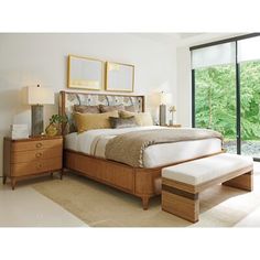 a bedroom with a large bed, dresser and window overlooking the trees in the background