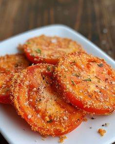 sliced tomatoes on a white plate with seasoning sprinkles and pepper flakes