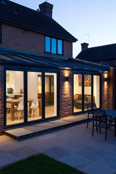 an outdoor dining area is lit up at night with lights on the patio and table