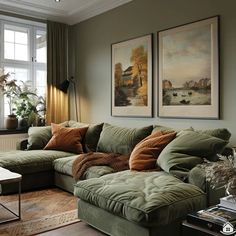 a living room with green couches and paintings on the wall