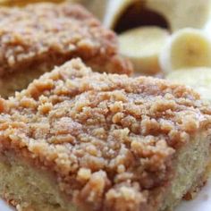 two pieces of cake sitting on top of a white plate next to bananas and other foods