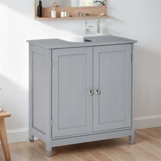 a bathroom vanity with two doors and a sink in the middle, on a wooden floor