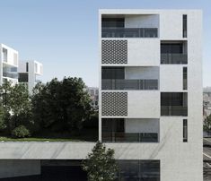 a tall white building with balconies on the side and trees in front of it