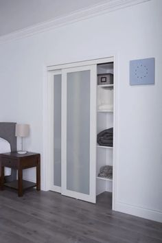 an empty bedroom with a bed, nightstand and sliding glass closet doors that open to reveal a walk - in closet