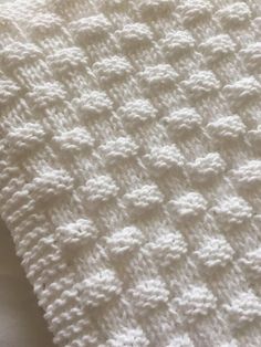 a white crocheted blanket laying on top of a bed