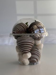 chocolate covered strawberries in a plastic container on a table with white and black rocks