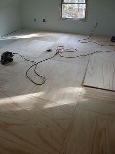 an unfinished room with hard wood floors and electrical cords on the floor in front of a window