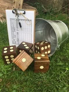 wooden dices sitting in the grass next to a metal bucket