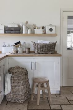 a kitchen with white cabinets and baskets on the counter top, along with two stools