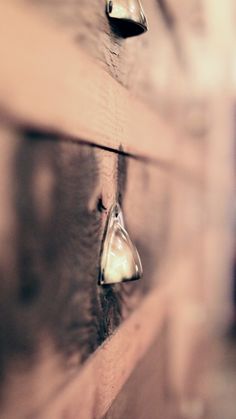 two pieces of wood are hanging on the wall with other things in it's shadow