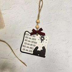 a christmas ornament hanging on a wall with a red ribbon around it's neck