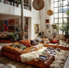 a living room filled with lots of furniture and plants on top of the floor in front of large windows