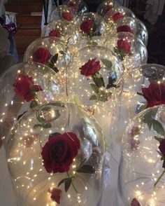 several wine glasses with roses in them and lights on the rims are sitting on a table