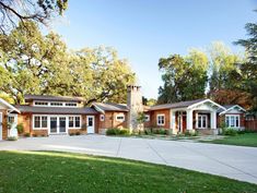 a large brick house sitting on top of a lush green field next to a forest