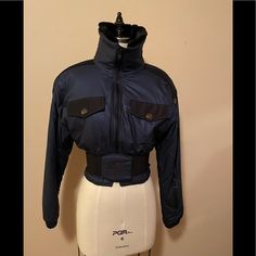 Vintage Nils Ski Jacket Size 6, Cinched Waist With An Elasticized Belt With Center Crest. The Belt Is Attached In The Back And Fastens In The Front With Velcro. Breast Flap Pockets That Open To A Zippered Pocket, Left Sleeve Zippered Pocket And Inside Zippered Pocket (Shown In Picture Of The Jacket Lining). It’s A Knockout On Or Off The Slopes! Fitted Techwear Outerwear For Winter, Winter Nylon Cropped Jacket With Long Sleeves, Fitted Ski Outerwear For Ski Season, Fitted Outerwear For Ski Season, Fitted Blue Cropped Winter Jacket, Fitted Cropped Winter Jacket, Fitted Navy Outerwear For Streetwear, Fitted Blue Cropped Jacket For Fall, Fitted Black Skiing Outerwear