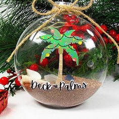 a christmas ornament with a palm tree on it and the words deck the palms written in black