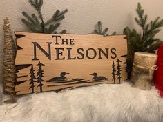 a wooden sign that says the nelsons on it next to some christmas trees and presents