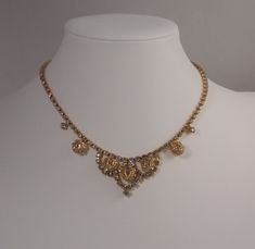 *Time period:  1960's *Maker's mark:  CATHE *Style:  Choker necklace *Materials:  Clear Rhinestones & Beads *Color:  Yellow gold-toned metal; intricate leaf detailing *Length:  approx. 15 3/4 inches end to end *Height of Center:  approx. 1 1/8th Inches *Fastener: Hook Closure *Condition:  Very good to excellent vintage/pre-loved condition *Free standard shipping to the USA         Gift boxed for your gift giving convenience (The quarter in the photographs is only to assist with size comparison a Vintage Choker Necklace, Vintage Choker, Jewelry Lookbook, Gold Choker, Size Comparison, Beaded Choker Necklace, Wedding Jewellery Necklace, Time Period, Rhinestone Bead