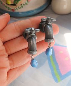 someone is holding some kind of earrings with blue beads in their hand and it looks like they have been made out of metal