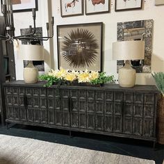 two lamps are sitting on top of a sideboard in a room with pictures above it