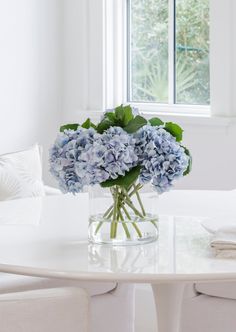 a vase filled with blue flowers sitting on top of a white table