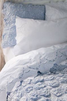 an unmade bed with blue and white linens