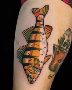 a colorful fish and skull tattoo on the thigh