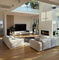 a modern living room with white furniture and large windows on the wall, along with hardwood flooring