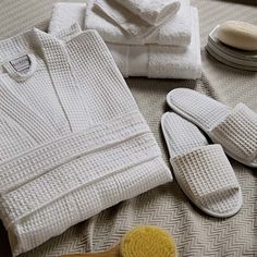 towels and slippers are laid out on a bed next to a hair brush, comb and soap dispenser