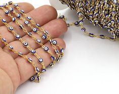 a hand holding a chain with evil eyes on it and a cup in the background