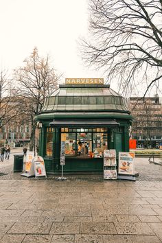 a small green building sitting on the side of a street