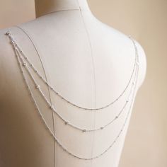 a white mannequin with silver beads on it's neck and two rows of chain