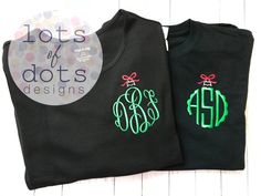 two black shirts with green and red monogrammed letters on them, one has a bow