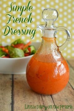 an orange liquid in a glass bottle next to a bowl of salad