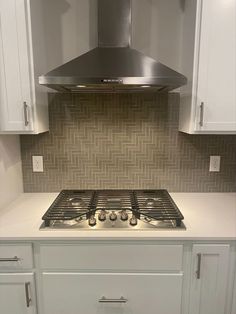 a stove top oven sitting inside of a kitchen next to white cupboards and drawers