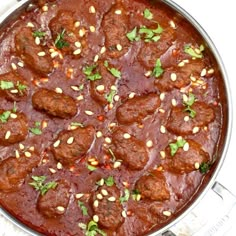 meatballs in tomato sauce with pine nuts and parsley on top, ready to be eaten