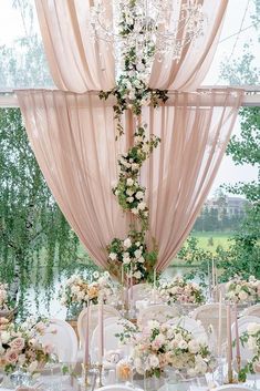 the table is set with white and pink flowers, candles, and chandeliers