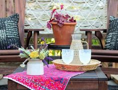 a table topped with two vases filled with flowers on top of a wooden table