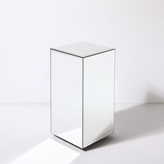 a white cube shaped object sitting on top of a white floor next to a wall