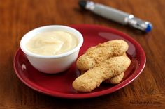 a red plate topped with chicken nuggets next to a bowl of ranch dressing