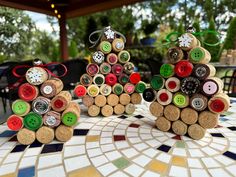 three wine cork christmas trees sitting on top of a mosaic tile table with green and red buttons