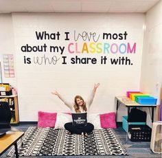 a woman sitting on top of a bed in front of a wall with words written on it