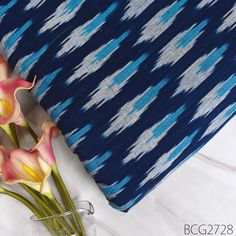 flowers in a vase next to a blue and white pillow