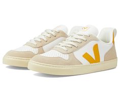 VEJA Kids Small V-10 L Chromefree (Big Kid) - Kid's Shoes : Extra/White/Ouro/Almond : The primary materials that compose this product contain a minimum of 20 percent recycled content. , Transform your sporty look effortlessly by opting for the super comfy VEJA Kids Small V-10 L Chromefree Sneakers. Chrome-free leather upper. Recycled polyester lining. Sugarcane and organic cotton insole. Classic lace-up closure. Brand's signature monogram on the upper. Pull loops for easy wear and removal. Padde Sporty Sneakers With White Sole For Everyday, Sporty White Sole Sneakers For Everyday, Sporty Everyday Sneakers With White Sole, Sporty Sneakers With Perforations For Everyday, Sporty Orange Low-top Canvas Shoes, Yellow Low-top Sneakers For Playtime, Toddler Veja Shoes, Beige Kids Shoes, Tommy Hilfiger Low-top Sneakers With White Sole